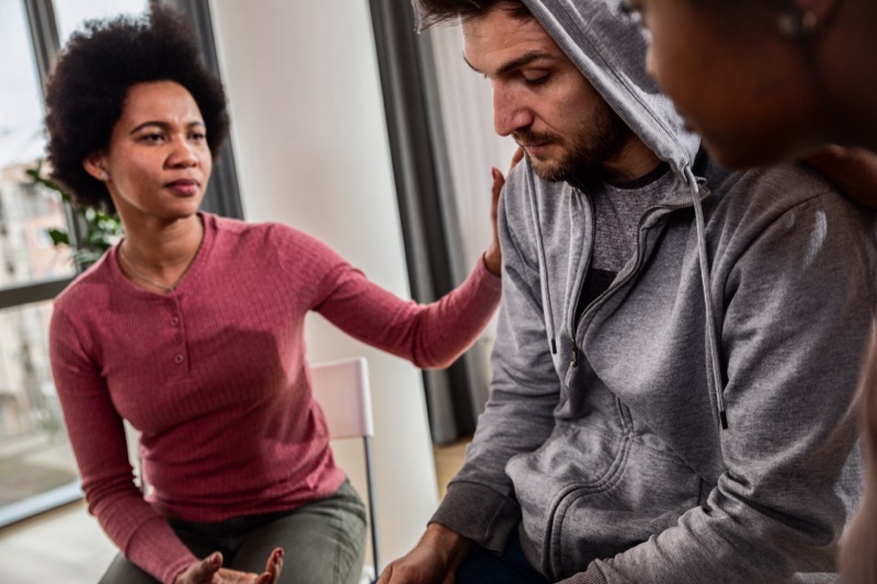 Peers offering support to a man during a group session